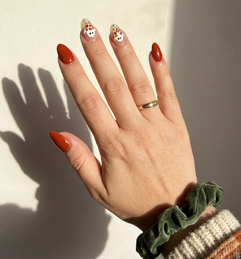 Rust orange manicure with small hand-painted accents